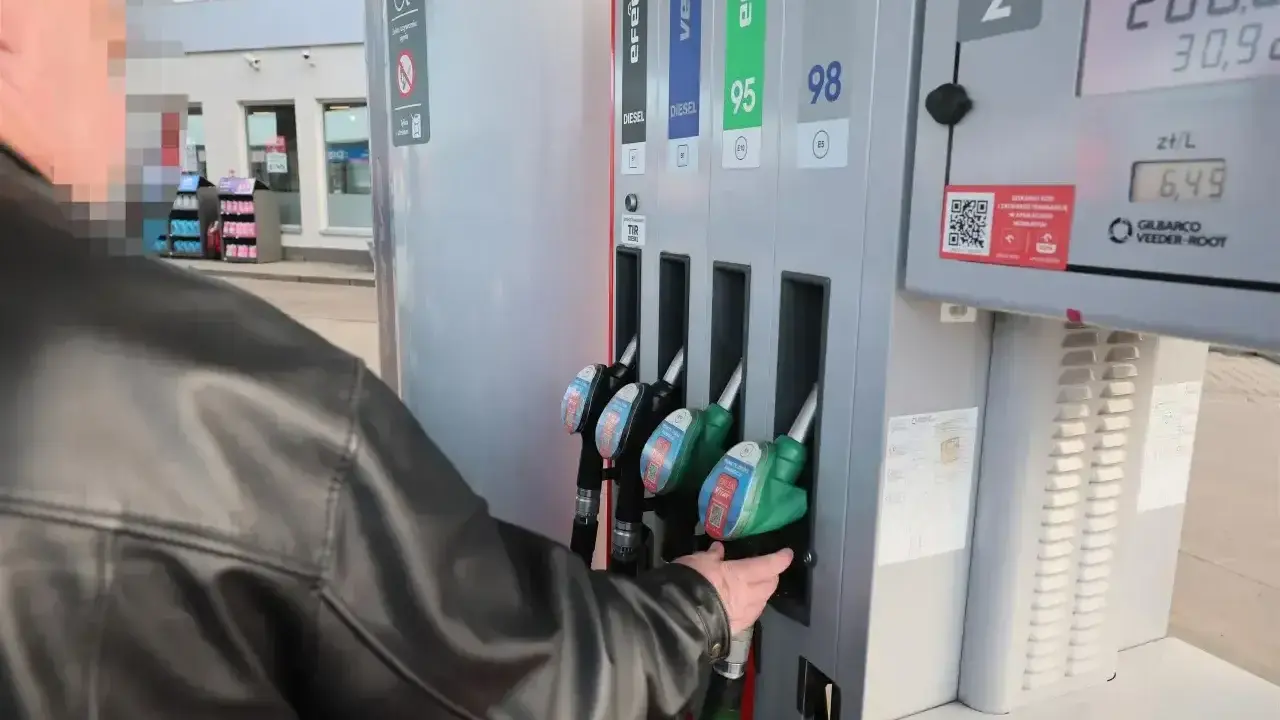 Mężczyzna tankuje paliwo verva na stacji. Wybiera dystrybutor z zieloną końcówką.
