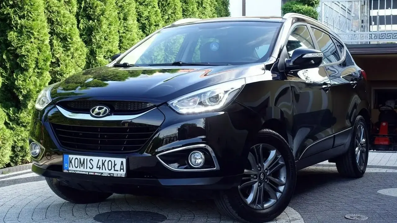Czarny Hyundai ix35 2.0 benzyna + LPG, lśniący na podjeździe przed zielonym żywopłotem.