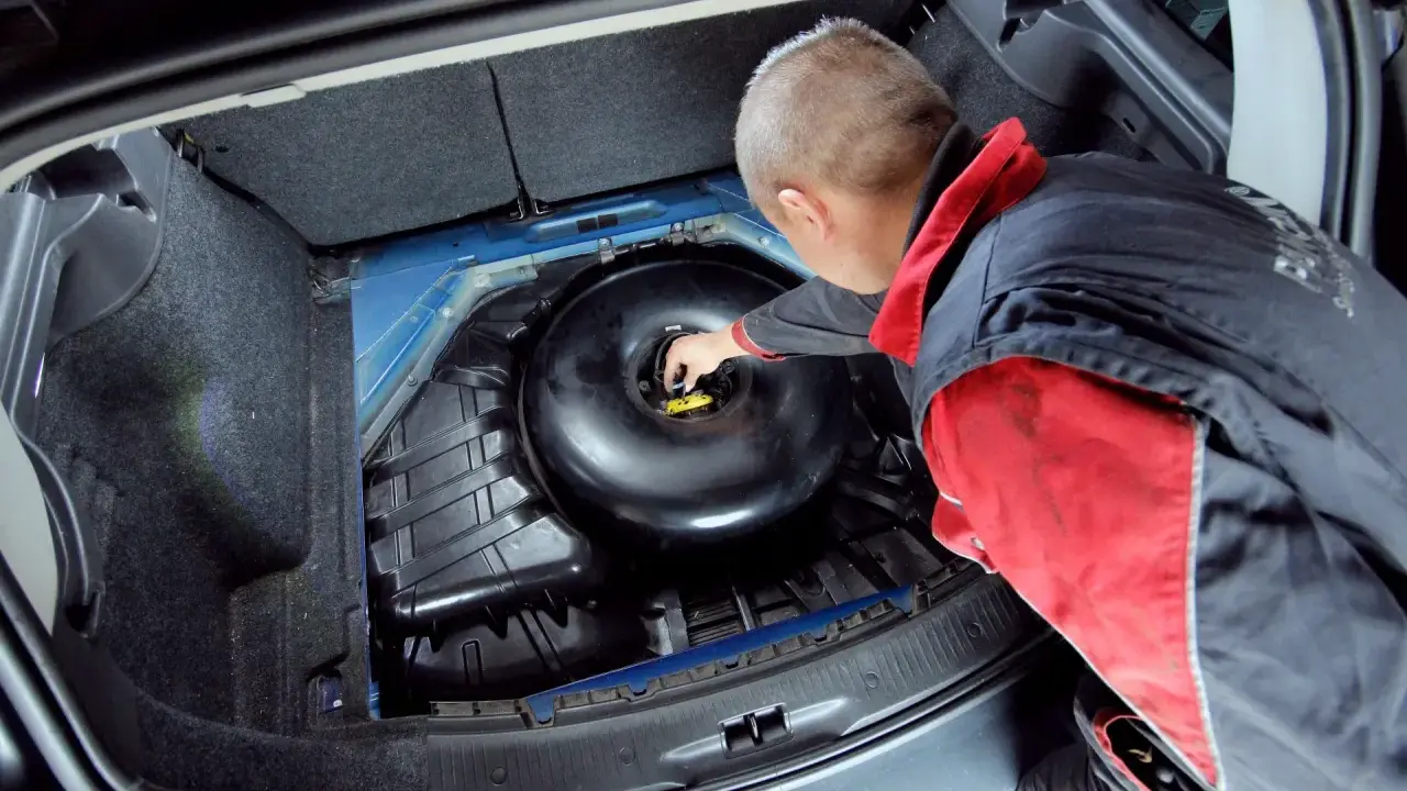 Mechanik sprawdza butlę LPG w bagażniku. Dowiedz się, jaki jest koszt wymiany butli LPG i kiedy jest ona konieczna.