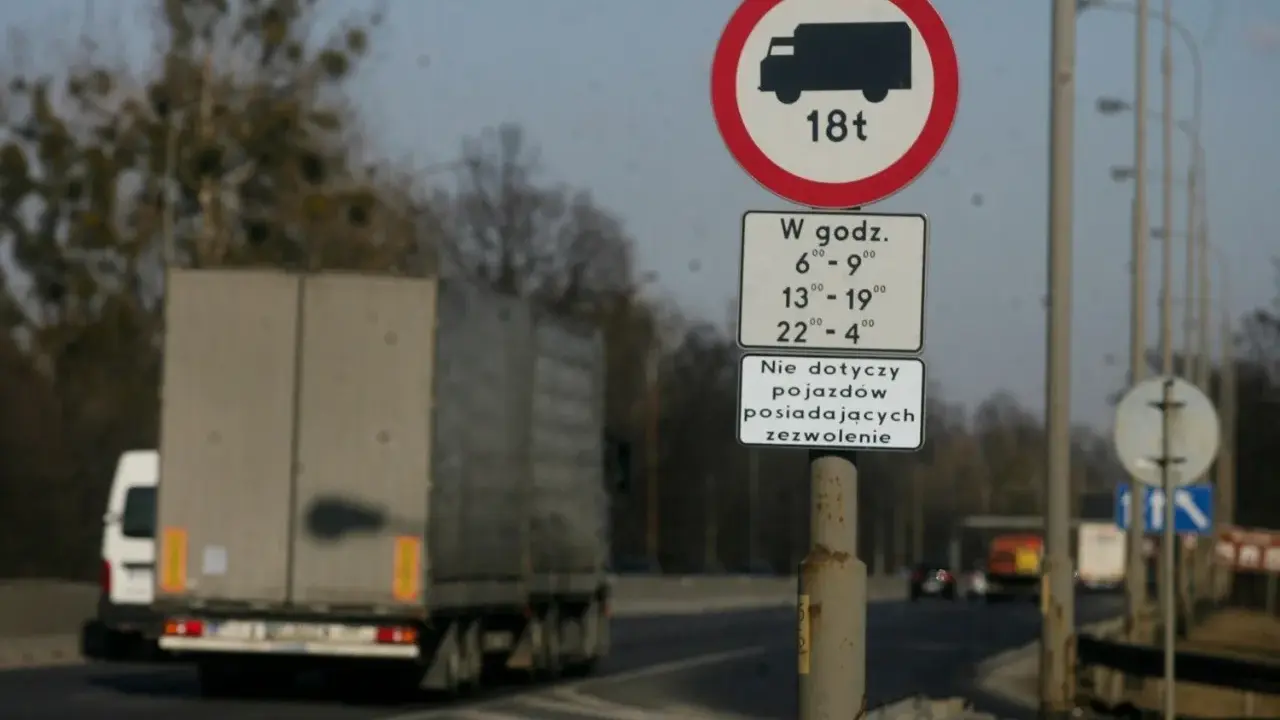 Znak zakazu ruchu dla ciężarówek powyżej 18t w określonych godzinach. Czy ciężarówki mogą jeździć w niedzielę? Ten znak odpowiada.