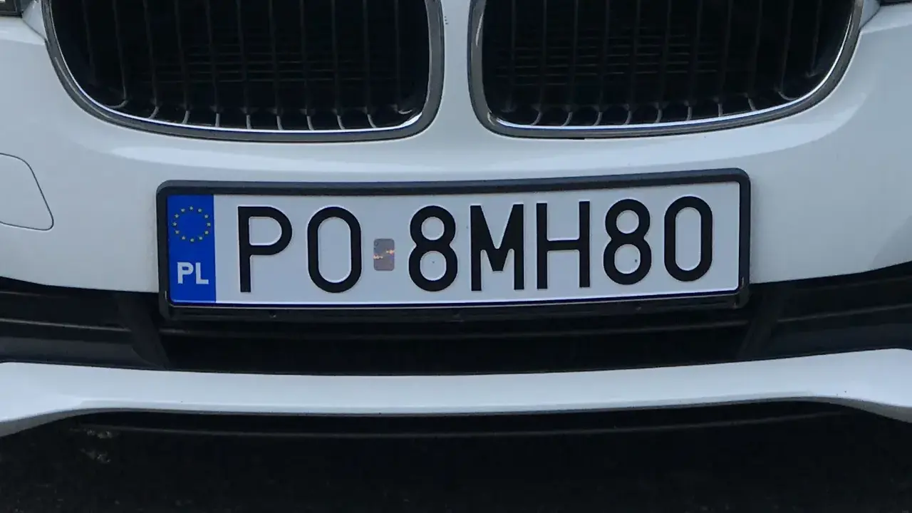 Biała tablica rejestracyjna z kodem PO 8MH80, z niebieskim paskiem UE i literami PL.
