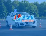 Biały samochód z literą "L" na dachu i pachołkami na placu manewrowym. To idealne miejsce na praktyczny egzamin na prawo jazdy.