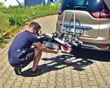 Mężczyzna montuje tablicę rejestracyjną na bagażnik rowerowy zamontowany z tyłu samochodu.