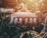 Silnik samochodowy z widocznym kolektorem dolotowym, pełen przewodów i części. To właśnie kolektor odpowiada za doprowadzenie powietrza do cylindrów.