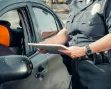 Policjant spisuje dane podczas kontroli drogowej, być może w związku z wymianą karty kierowcy.