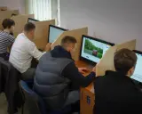 Ludzie siedzą przy komputerach, rozwiązując testy. Tak sprawdzisz, jak zdałeś egzamin teoretyczny na prawo jazdy.