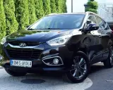 Czarny Hyundai ix35 2.0 benzyna + LPG, lśniący na podjeździe przed zielonym żywopłotem.