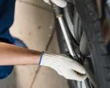 Mechanik w białej rękawiczce dokręca śruby koła kluczem dynamometrycznym. Ważne, by wiedzieć, ile nm dokręcać koła dla bezpieczeństwa.