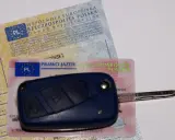 Kluczyk samochodowy leży na dowodzie rejestracyjnym i prawie jazdy. To komplet dokumentów do prowadzenia pojazdu.