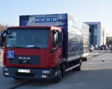 Czerwona ciężarówka MAN z literą "L" na masce i logo WORD. Na naczepie widnieje napis "WOJEWÓDZKI OŚRODEK RUCHU DROGOWEGO". To miejsce, gdzie składa się wniosek PKZ.