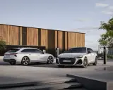 Dwa białe Audi, sedan i Avant, przed nowoczesnym budynkiem. Zastanawiasz się, jakie prawo jazdy na limuzynę?