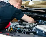 Mechanik pracuje przy silniku z instalacją gazową. Sprawdza podzespoły, by zapewnić optymalną cng cenę za litr.