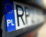 Zbliżenie na polską tablicę rejestracyjną z symbolem Unii Europejskiej. Litery "PL" i fragment numeru rejestracyjnego są wyraźne.
