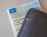 Dowód rejestracyjny pojazdu i brązowy portfel. Nieodebranie dokumentu może skutkować karą za nieodebranie dowodu rejestracyjnego.