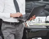 Mężczyzna w koszuli i krawacie sprawdza na laptopie, kiedy trzeba przerejestrować auto.