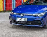 Niebieski Volkswagen Golf R z tablicą rejestracyjną PY 49819, zaparkowany przy kolorowym płocie.
