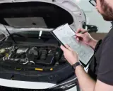 Mechanik sprawdza listę kontrolną przed przeglądem samochodu, zastanawiając się, ile kosztuje przegląd.