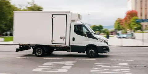 Biała chłodnia na podwoziu Iveco Daily, idealna do transportu towarów wymagających niskiej temperatury. Posiadanie prawa jazdy C1 pozwala na prowadzenie tego typu pojazdu.