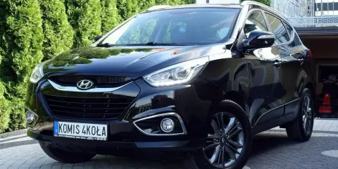 Czarny Hyundai ix35 2.0 benzyna + LPG, lśniący na podjeździe przed zielonym żywopłotem.
