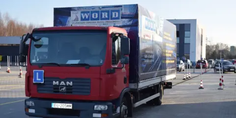 Czerwona ciężarówka MAN z literą "L" na masce i logo WORD. Na naczepie widnieje napis "WOJEWÓDZKI OŚRODEK RUCHU DROGOWEGO". To miejsce, gdzie składa się wniosek PKZ.