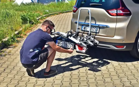 Mężczyzna montuje tablicę rejestracyjną na bagażnik rowerowy zamontowany z tyłu samochodu.