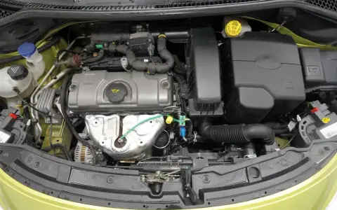 Silnik w Peugeot 207, z widocznymi elementami układu dolotowego i chłodzenia.