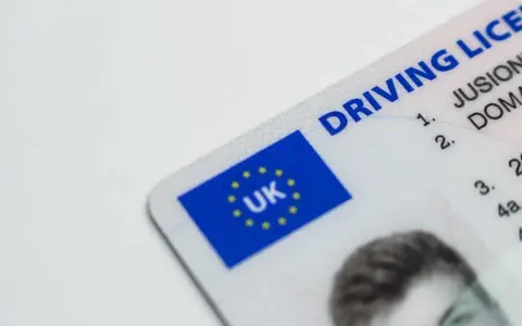 Brytyjskie prawo jazdy. Czy można jeździć oczekując na wymianę prawo jazdy? Dokument z flagą UK.