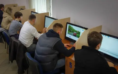 Ludzie siedzą przy komputerach, rozwiązując testy. Tak sprawdzisz, jak zdałeś egzamin teoretyczny na prawo jazdy.