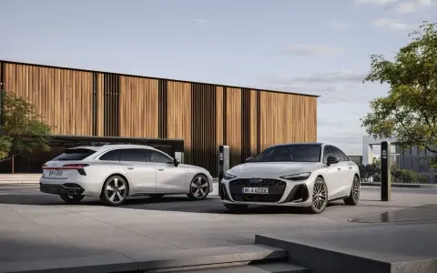 Dwa białe Audi, sedan i Avant, przed nowoczesnym budynkiem. Zastanawiasz się, jakie prawo jazdy na limuzynę?