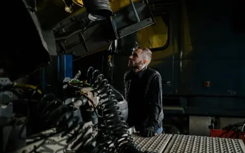 Mechanik analizuje przedmuchy w silniku diesla objawy, badając skomplikowane przewody i elementy ciężarówki w warsztacie.