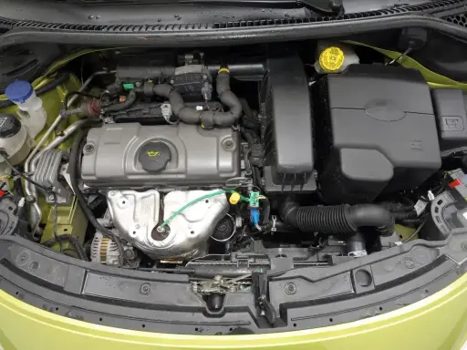 Silnik w Peugeot 207, z widocznymi elementami układu dolotowego i chłodzenia.