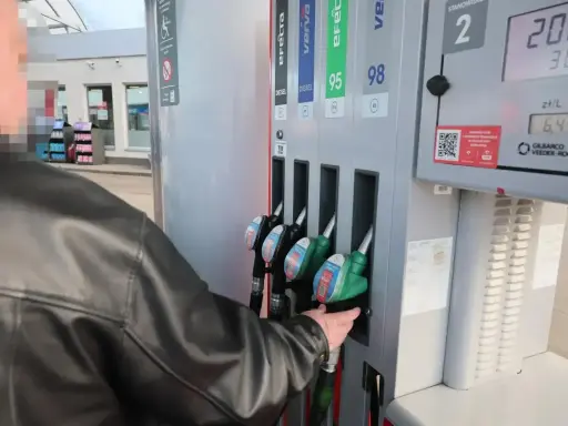 Mężczyzna tankuje paliwo verva na stacji. Wybiera dystrybutor z zieloną końcówką.