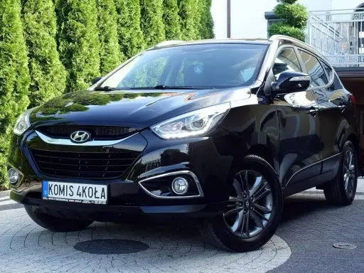 Czarny Hyundai ix35 2.0 benzyna + LPG, lśniący na podjeździe przed zielonym żywopłotem.