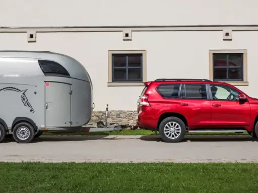 Czerwony SUV holuje przyczepę kempingową z koniem. Jaka kategoria na auto? SUV z przyczepą do przewozu zwierząt.