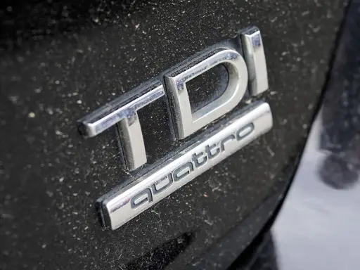 Emblemat TDI Quattro na zakurzonej czarnej karoserii. Zastanawiasz się, 2.0 tdi ile oleju potrzeba?