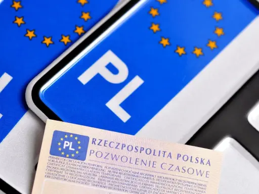 Pozwolenie czasowe pojazdu, dokument z symbolem PL i gwiazdkami UE, leży obok tablic rejestracyjnych.