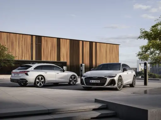 Dwa białe Audi, sedan i Avant, przed nowoczesnym budynkiem. Zastanawiasz się, jakie prawo jazdy na limuzynę?