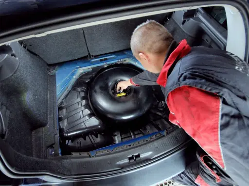 Mechanik sprawdza butlę LPG w bagażniku. Dowiedz się, jaki jest koszt wymiany butli LPG i kiedy jest ona konieczna.