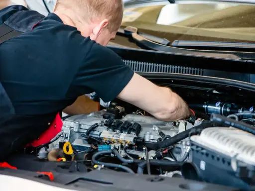 Mechanik pracuje przy silniku z instalacją gazową. Sprawdza podzespoły, by zapewnić optymalną cng cenę za litr.