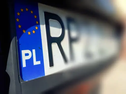 Zbliżenie na polską tablicę rejestracyjną z symbolem Unii Europejskiej. Litery "PL" i fragment numeru rejestracyjnego są wyraźne.