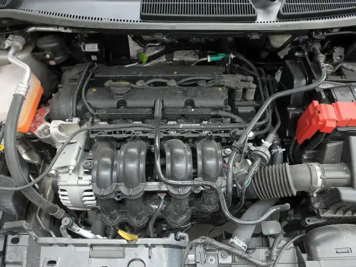 Silnik 1.6 HDI ile oleju? Widok komory silnika Forda, z widocznym kolektorem dolotowym, alternatorem i akumulatorem.