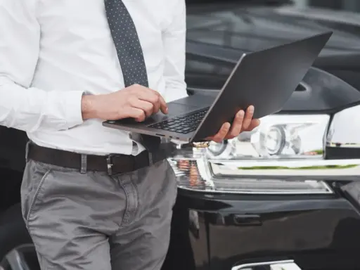 Mężczyzna w koszuli i krawacie sprawdza na laptopie, kiedy trzeba przerejestrować auto.