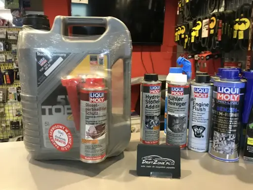 Duży kanister oleju silnikowego i kilka mniejszych preparatów do pielęgnacji samochodu, w tym dodatki do paliwa i płyny. Wszystkie oleje i preparaty to produkty marki Liqui Moly.