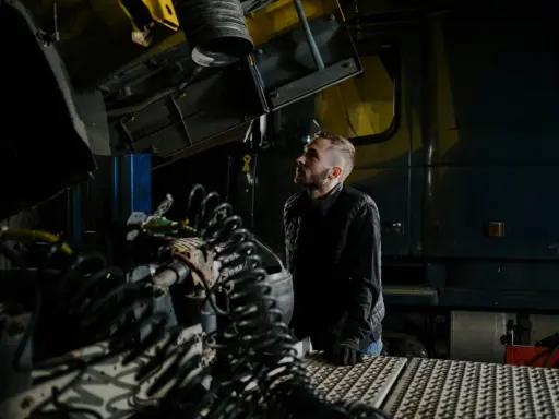 Mechanik analizuje przedmuchy w silniku diesla objawy, badając skomplikowane przewody i elementy ciężarówki w warsztacie.