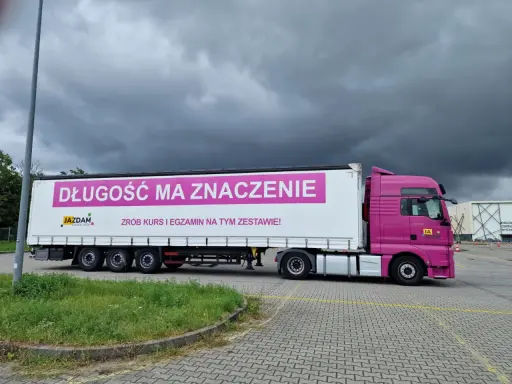Różowa ciężarówka z napisem "Długość ma znaczenie. Zrób kurs i egzamin na tym zestawie!" zachęca do zdania egzaminu kwalifikacji zawodowej kierowcy.