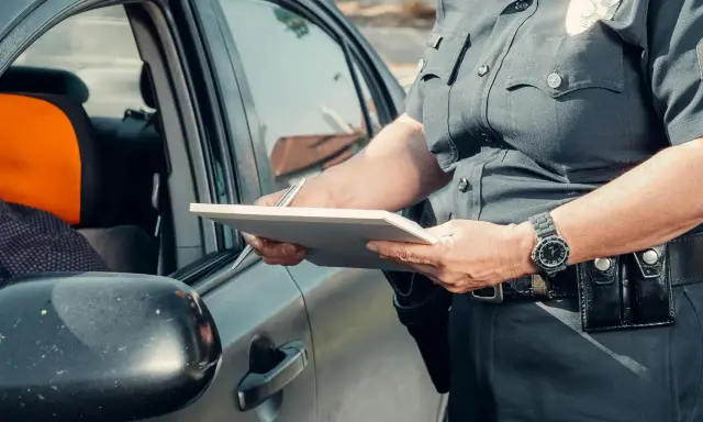 Policjant spisuje dane podczas kontroli drogowej, być może w związku z wymianą karty kierowcy.