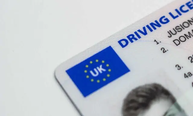 Brytyjskie prawo jazdy. Czy można jeździć oczekując na wymianę prawo jazdy? Dokument z flagą UK.