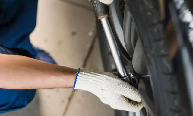 Mechanik w białej rękawiczce dokręca śruby koła kluczem dynamometrycznym. Ważne, by wiedzieć, ile nm dokręcać koła dla bezpieczeństwa.