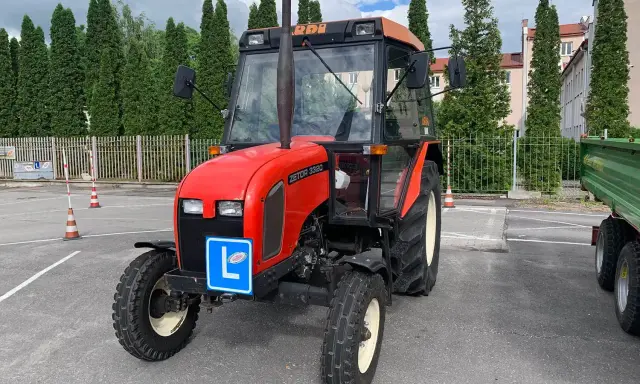 Czerwony traktor Zetor z tabliczką "L" na masce, gotowy do egzaminu na prawo jazdy na traktor.