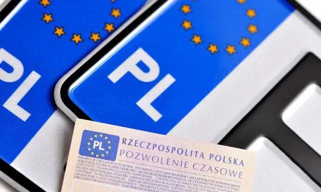 Pozwolenie czasowe pojazdu, dokument z symbolem PL i gwiazdkami UE, leży obok tablic rejestracyjnych.